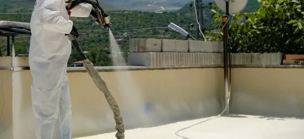 Man installing spray foam insulation in a commercial setting on the roof of a building