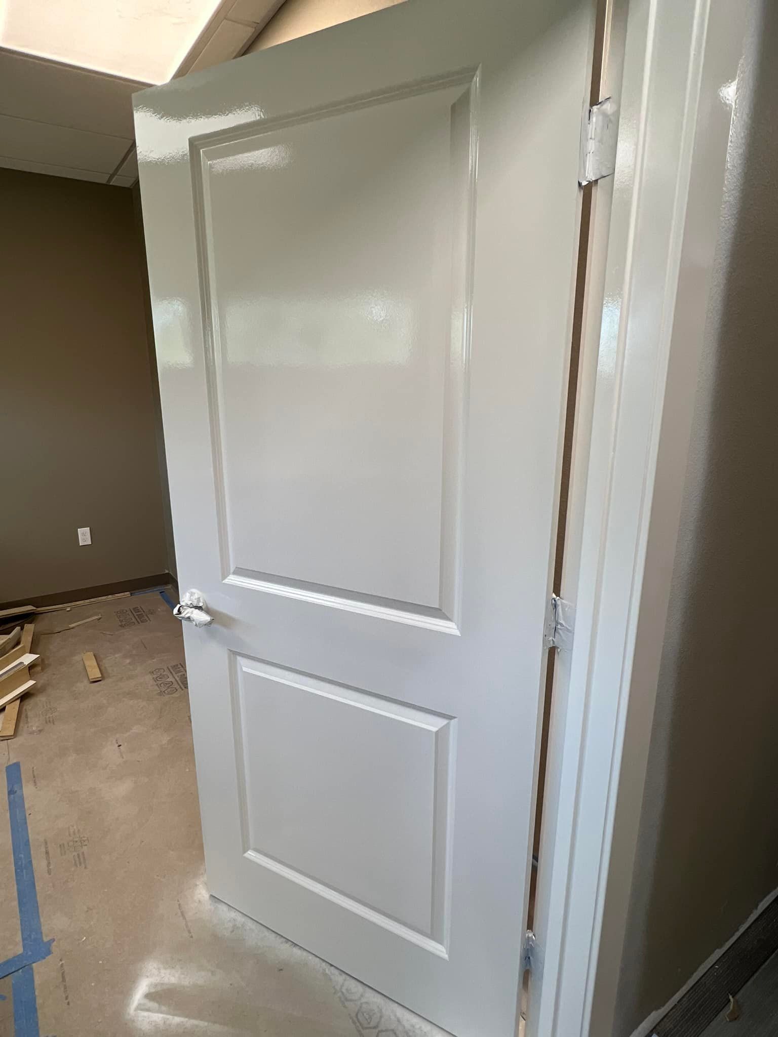 A white door is being painted in a room.