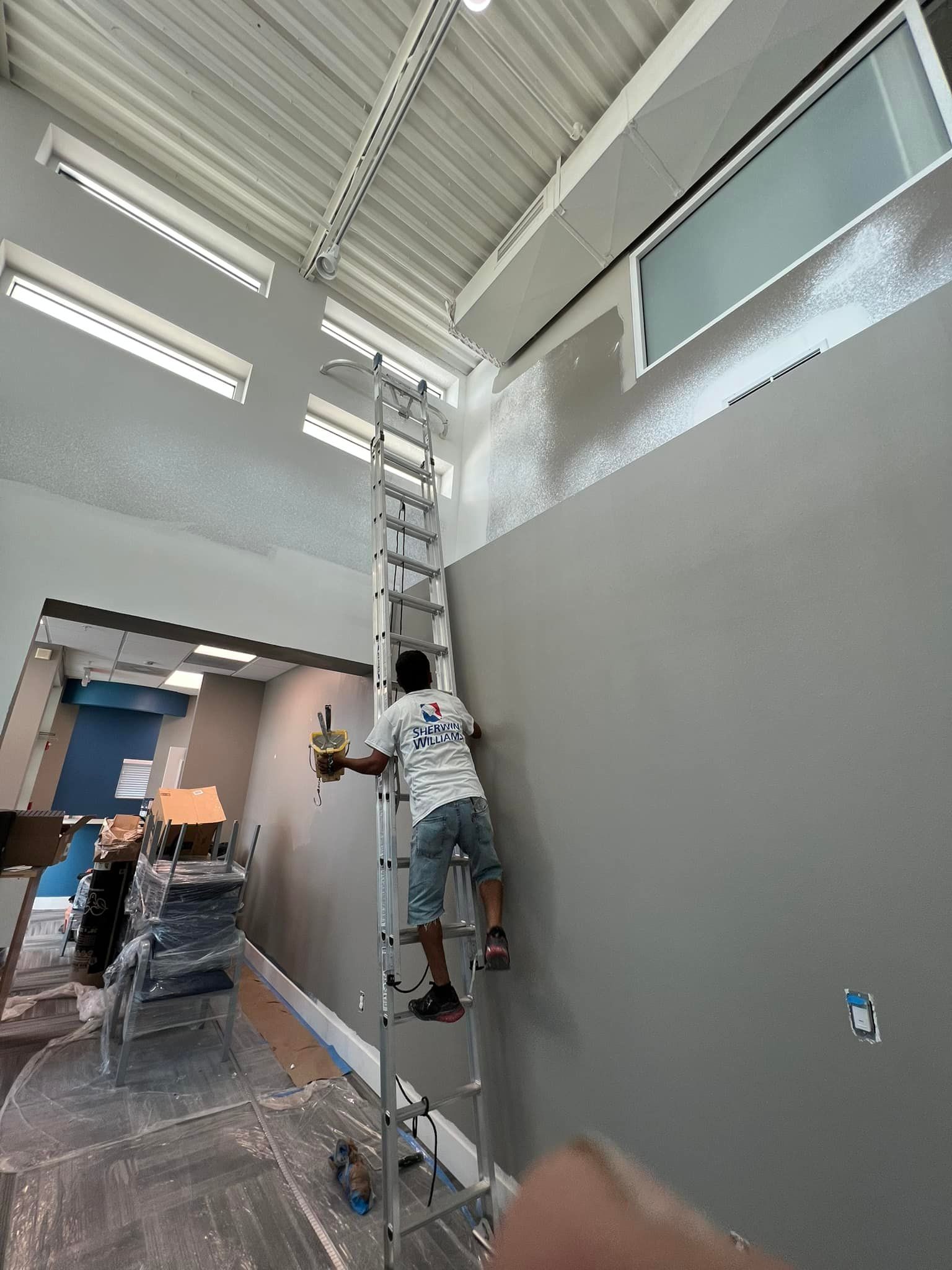 A man is climbing a ladder to paint a wall.