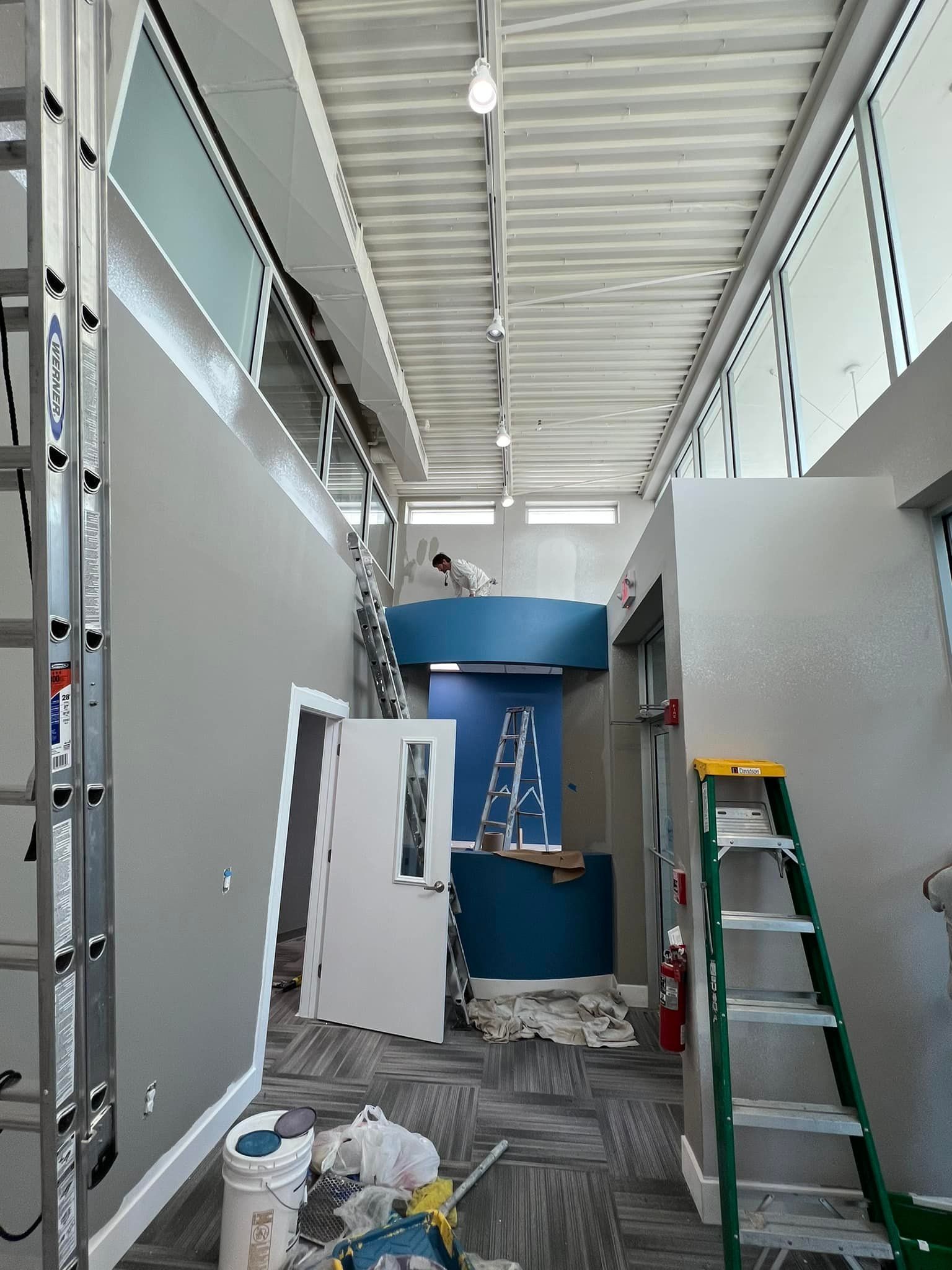 A room with a ladder and buckets of paint in it.