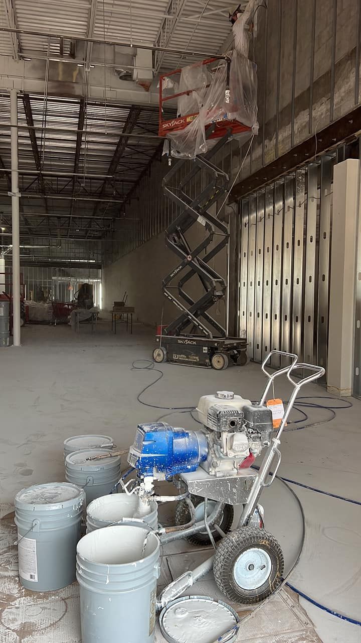 A spray paint machine is sitting on the floor of a building under construction.
