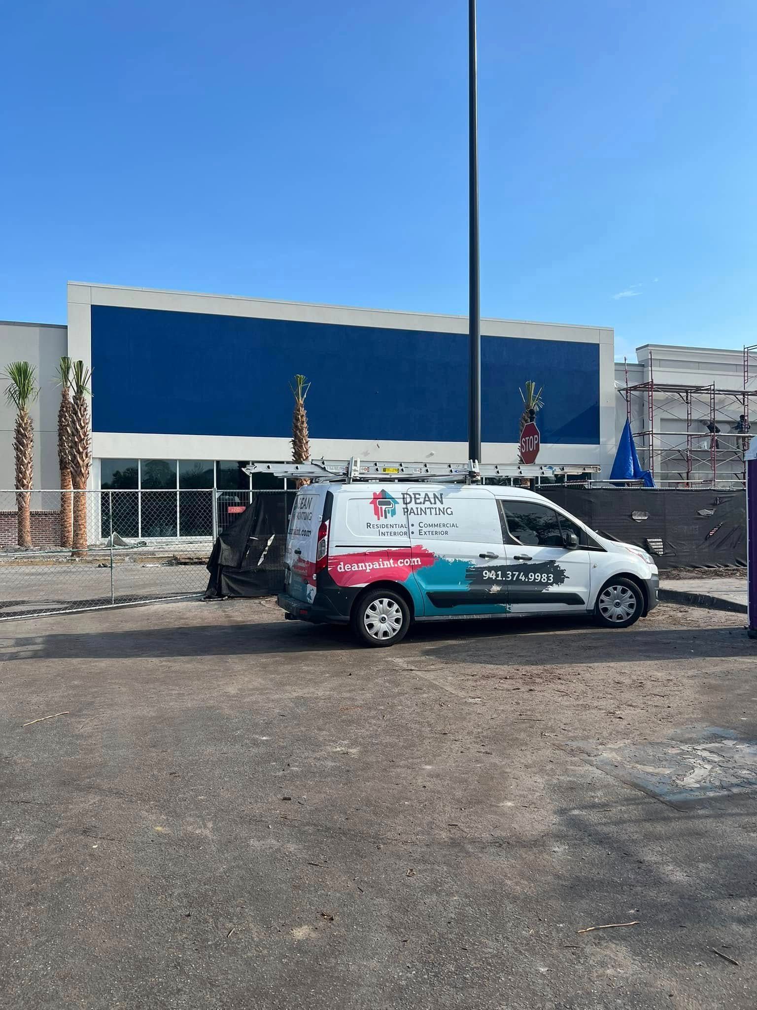 A white van is parked in front of a building under construction.