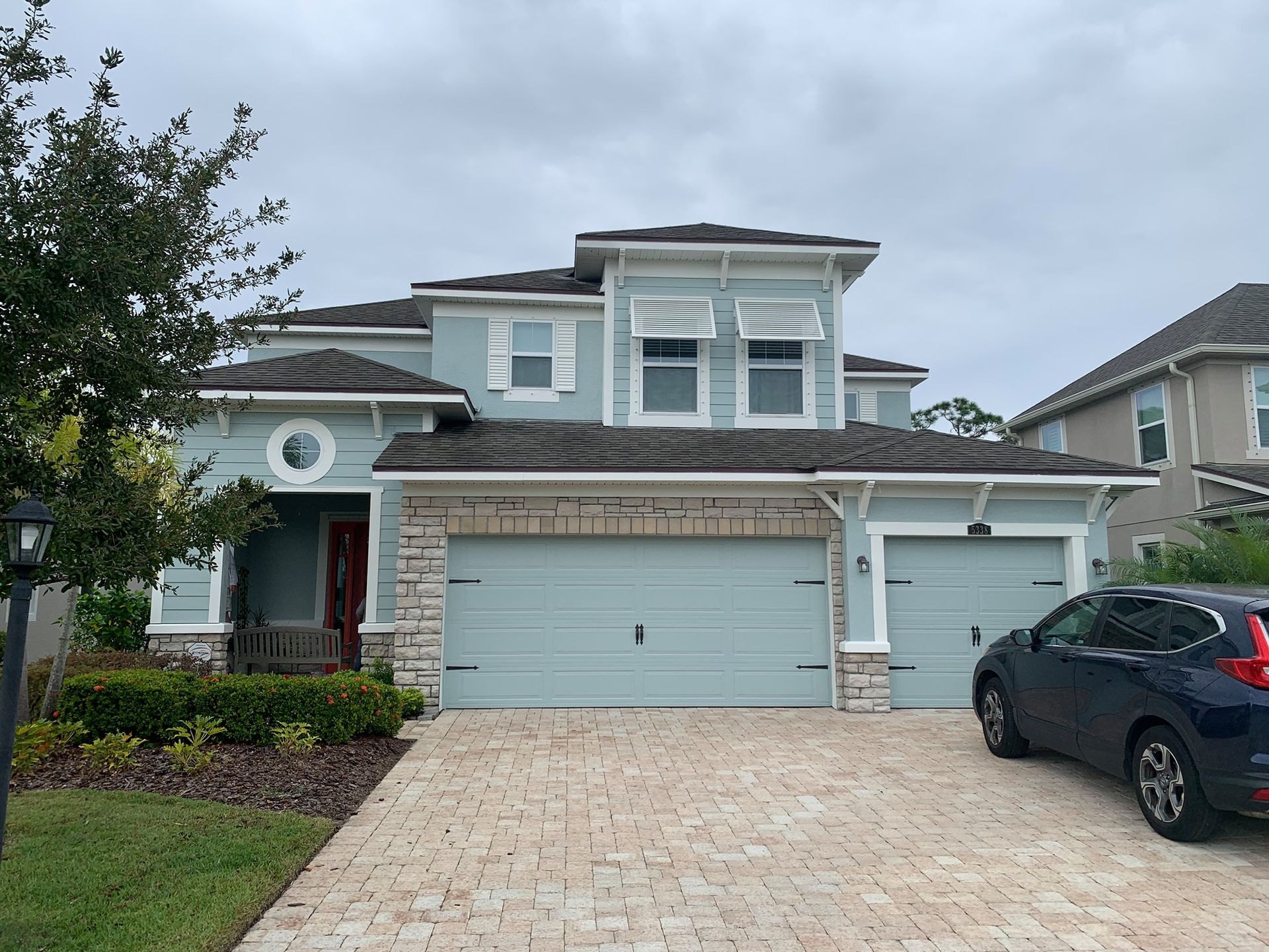 A car is parked in front of a large house.