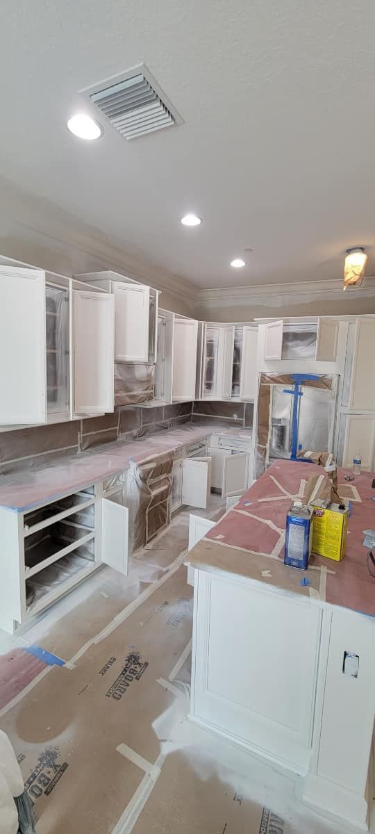 A kitchen under construction with white cabinets and a large island.