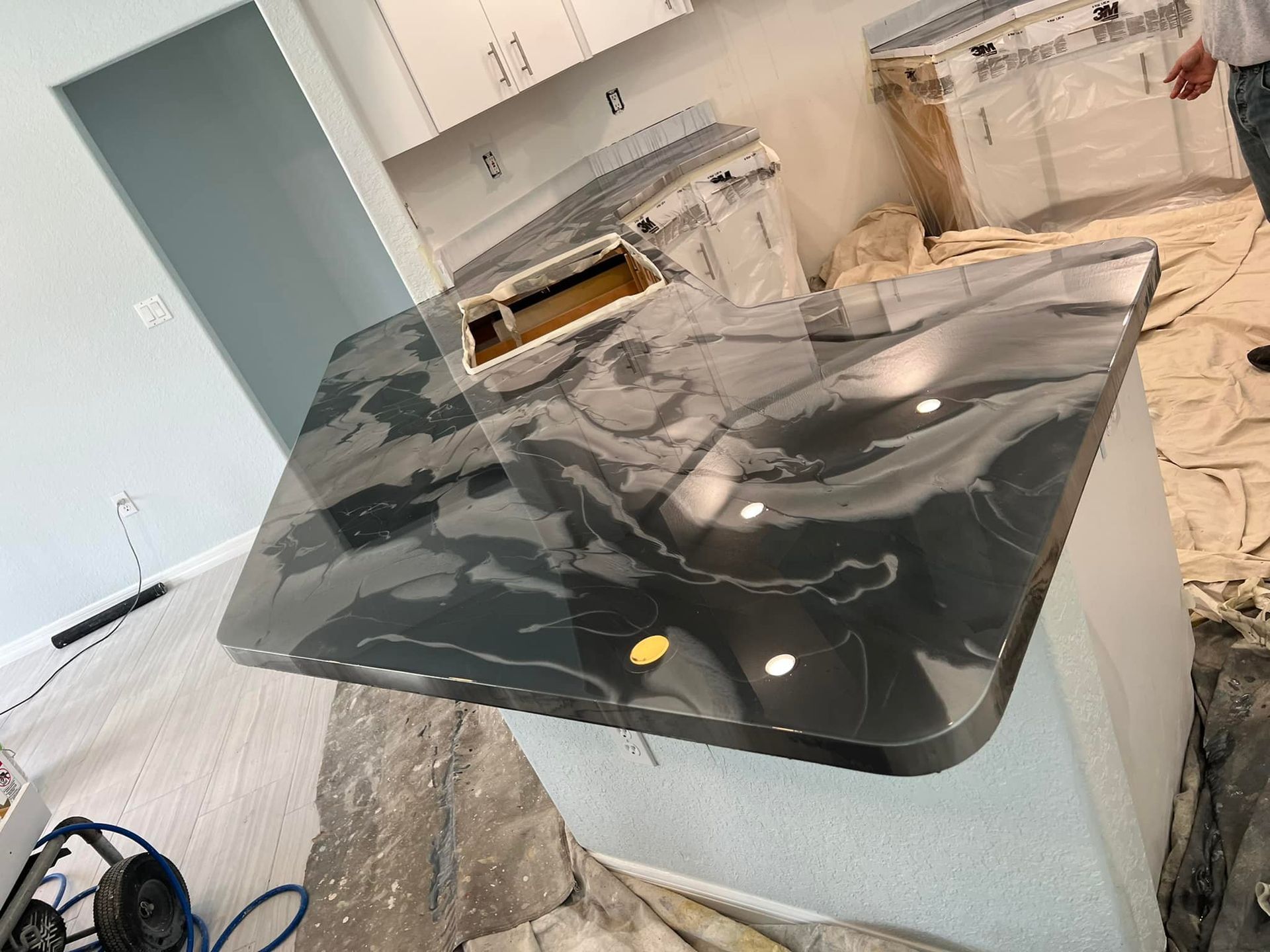 A black counter top is sitting on top of a white counter in a kitchen.