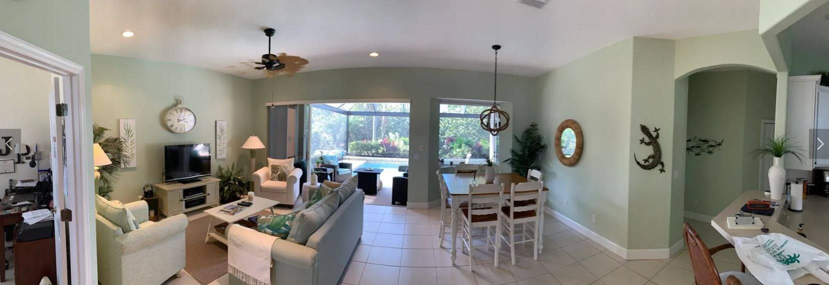 A panoramic view of a living room and dining room in a house.