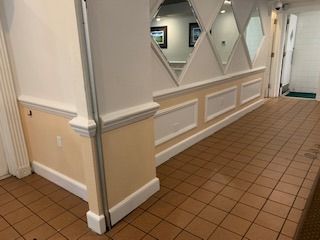 A hallway with a tiled floor and a wall with mirrors on it.