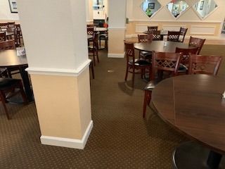 A restaurant with tables and chairs and a mirror on the wall.