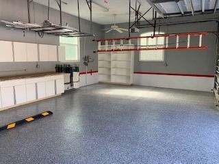 A large empty garage with a ladder hanging from the ceiling.
