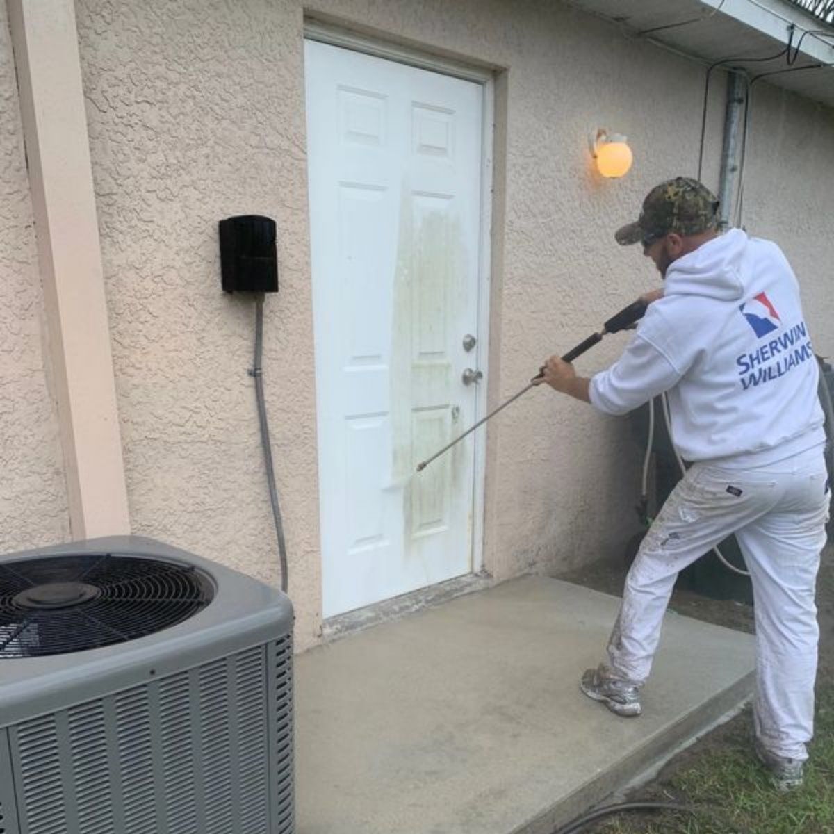 A man in a sherwin williams hoodie is cleaning a door