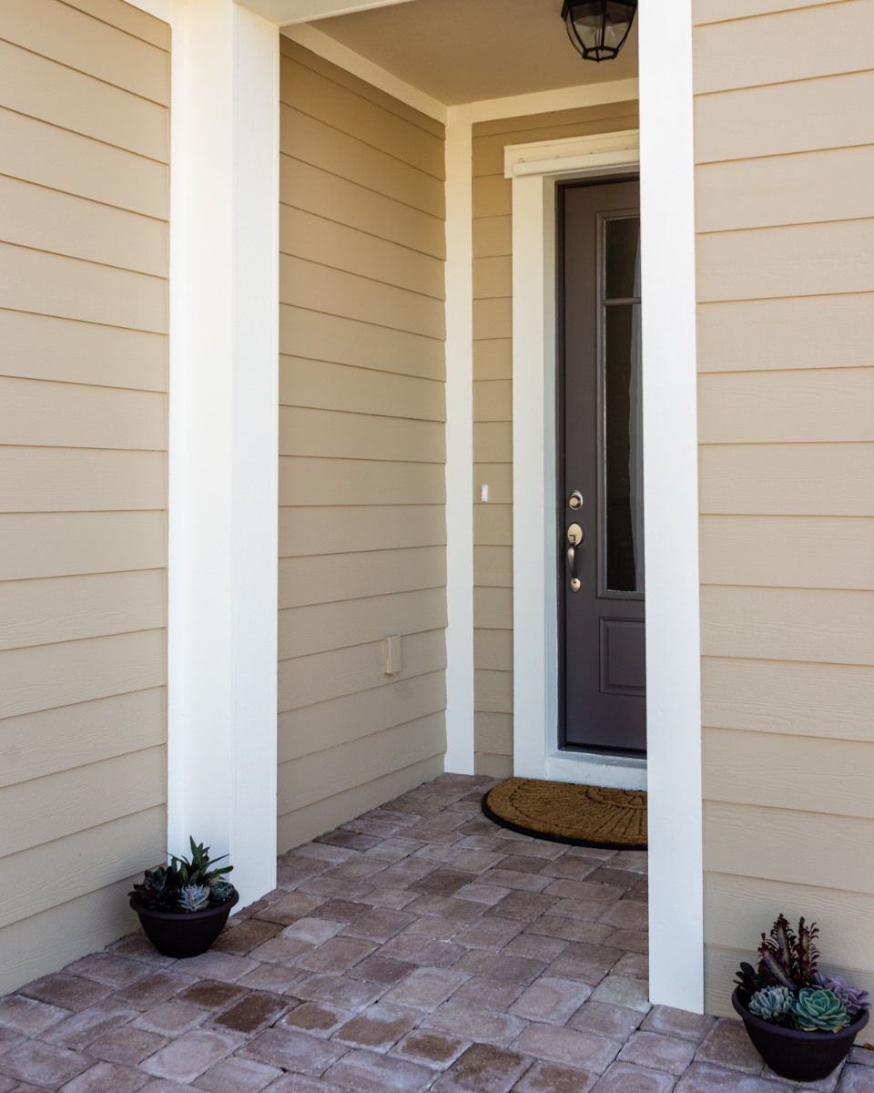 A porch with a gray door and potted plants