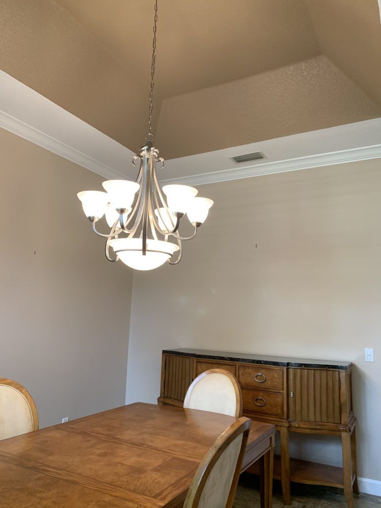A dining room with a table and chairs and a chandelier hanging from the ceiling.