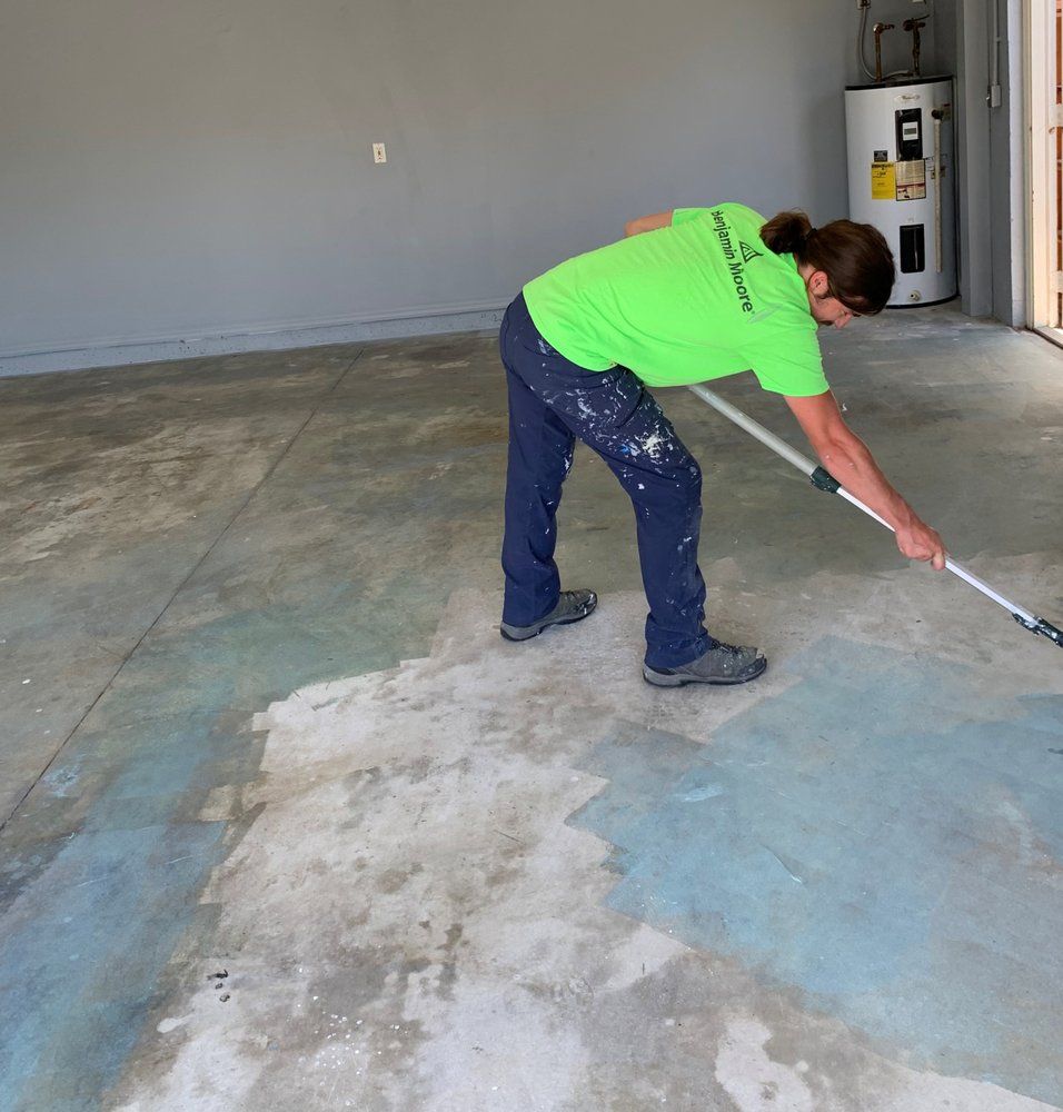 A person wearing a green shirt that says ' painting company ' on it