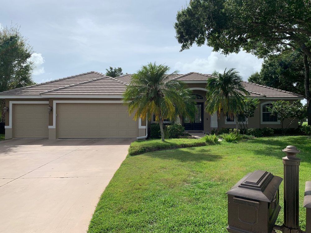 A large house with a driveway and palm trees in front of it
