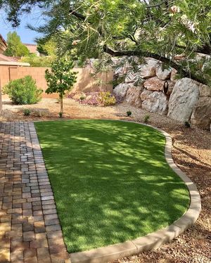 A backyard with a lush green lawn and a brick walkway.