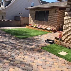 A house with a brick driveway and a lawn in front of it