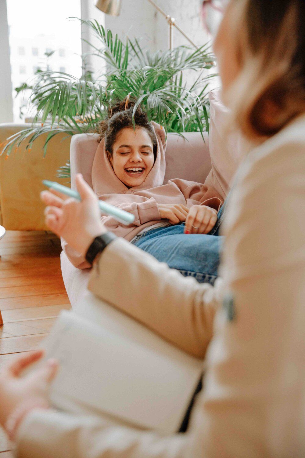 A woman is sitting on a couch talking to a young girl.