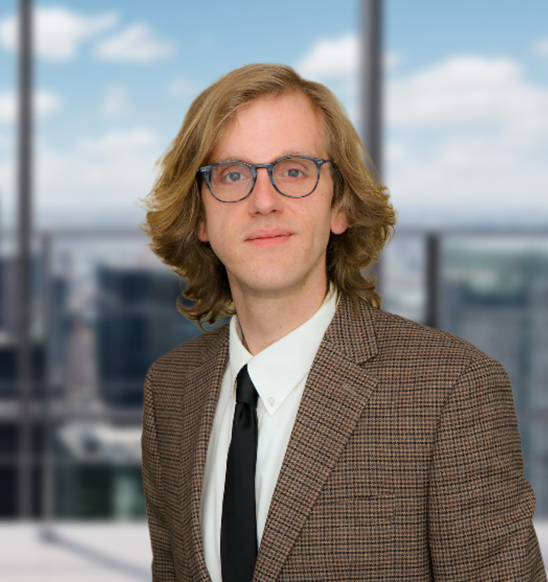 A man in a suit and tie is standing in front of a window.