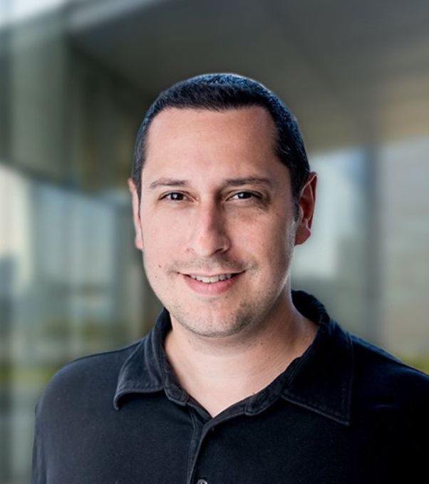 A man in a black shirt is smiling for the camera.