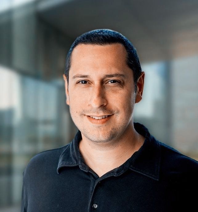 A man in a black shirt is smiling for the camera.