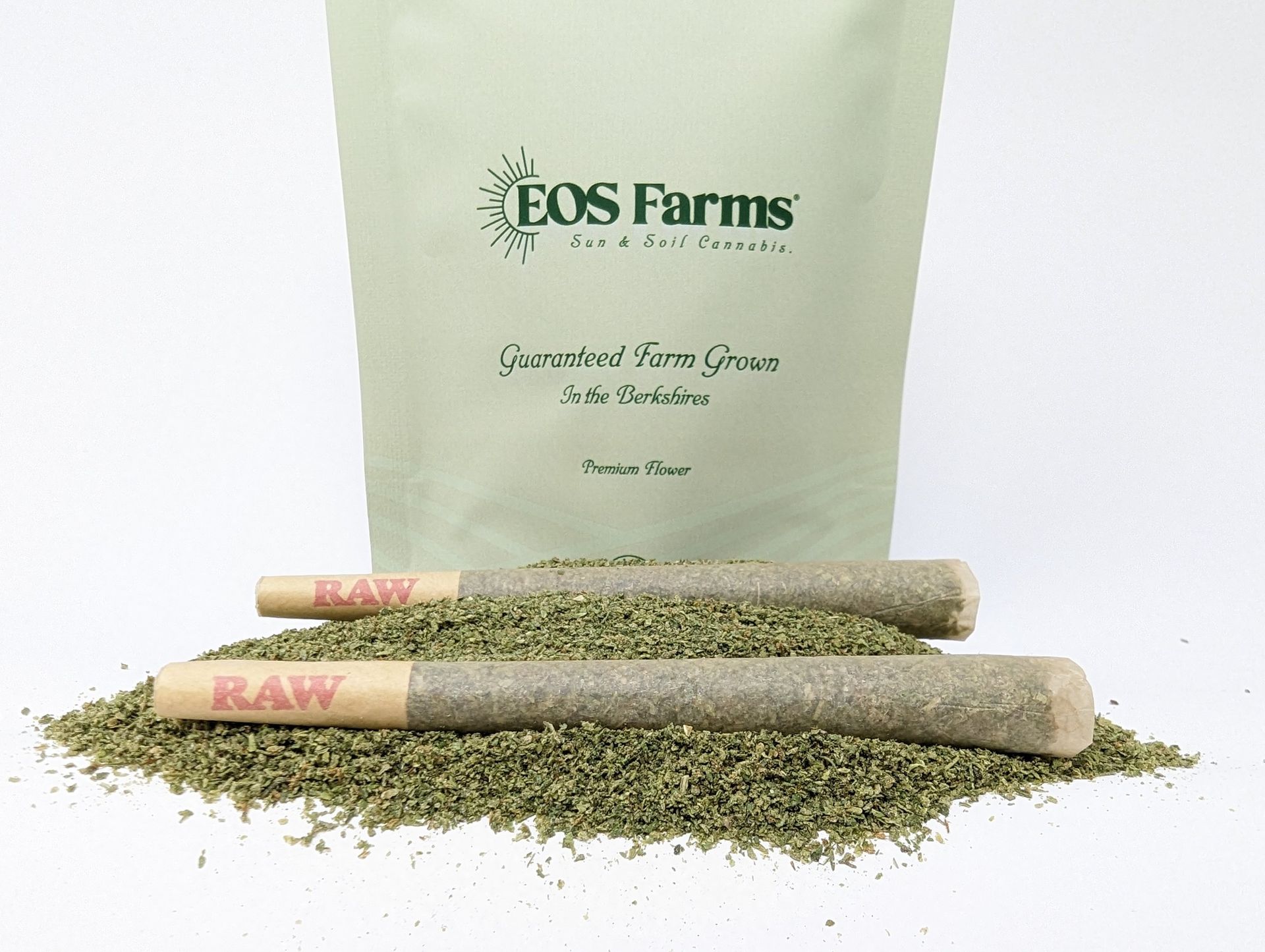Two eos farms pre rolled joints are sitting on a pile of dried grass