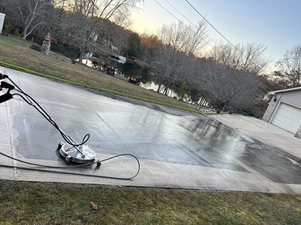 A person is using a pressure washer to clean a driveway.