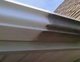 A close up of a gutter on a building with a building in the background.