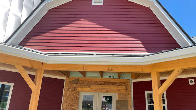 A red house with a wooden porch underneath it.