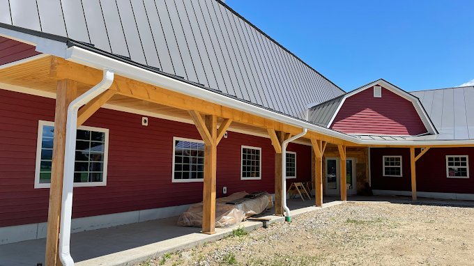 A red barn with a white roof and a wooden porch.