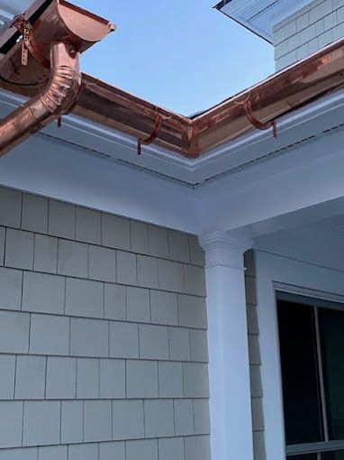A copper gutter is on the side of a house.