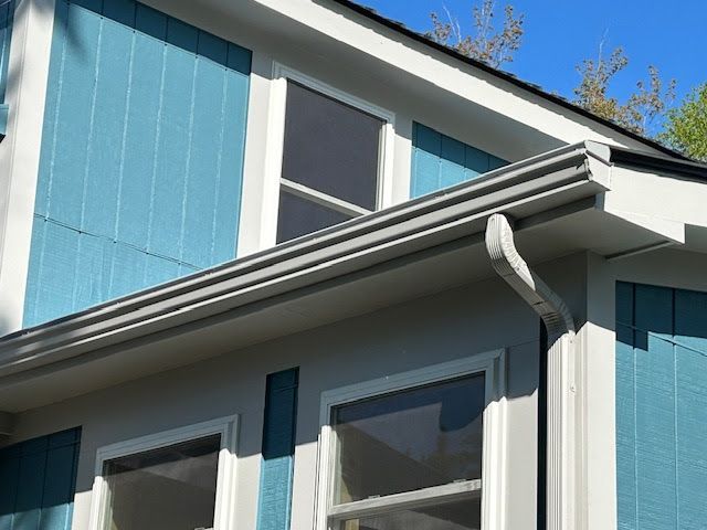 A blue and white house with a gutter on the side of it