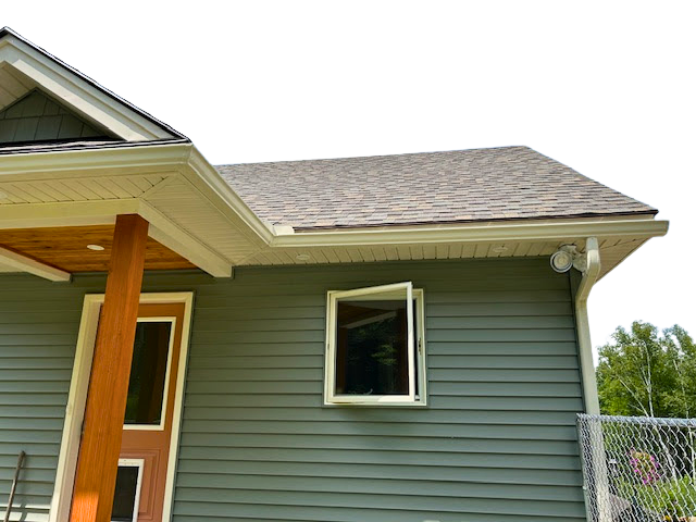 The back of a house with a wooden deck and black rain gutters