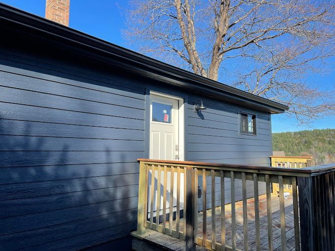 A blue house with a white door and a wooden deck.