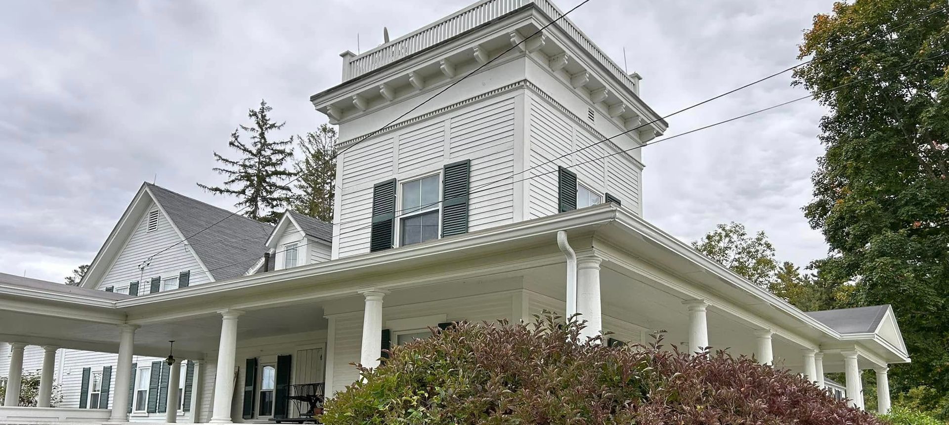 A large white house with a large porch and columns and white seamless rain gutters