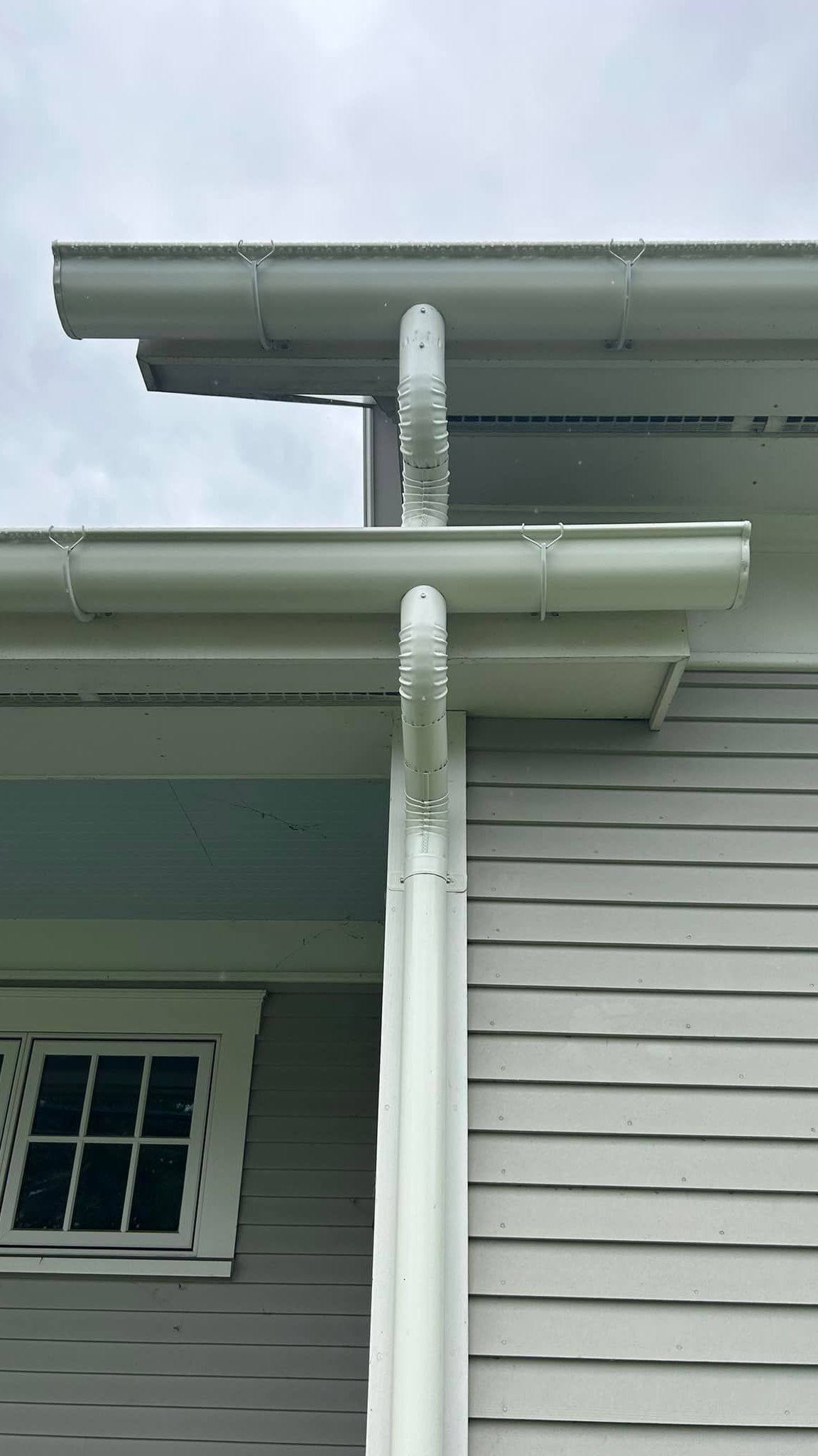 A close up of a white gutter on the side of a house.