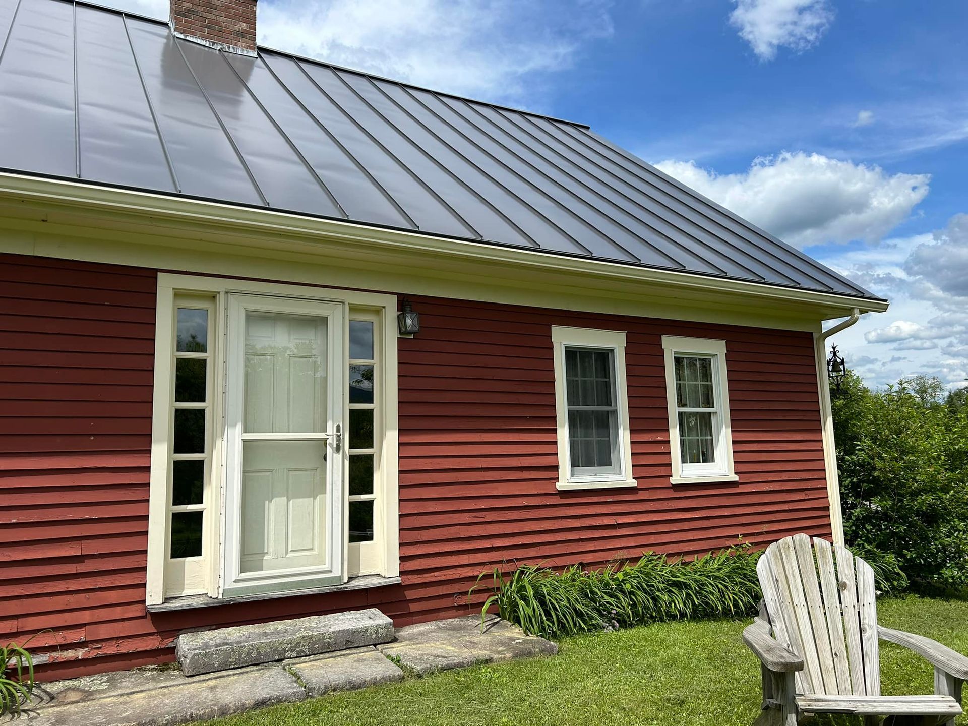 A red house with a wooden chair in front of it.