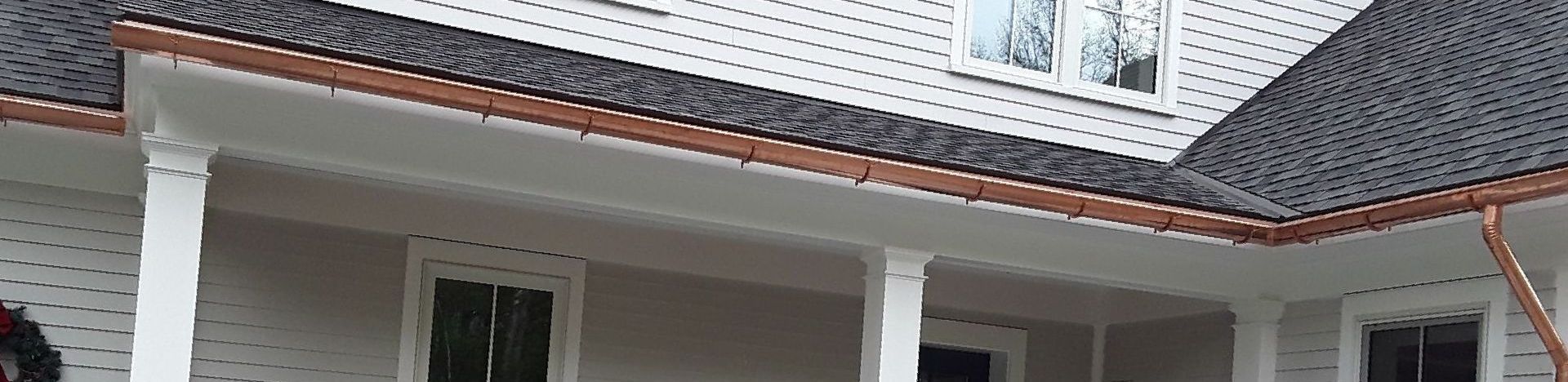 A house with a coper rain gutter on the porch roof