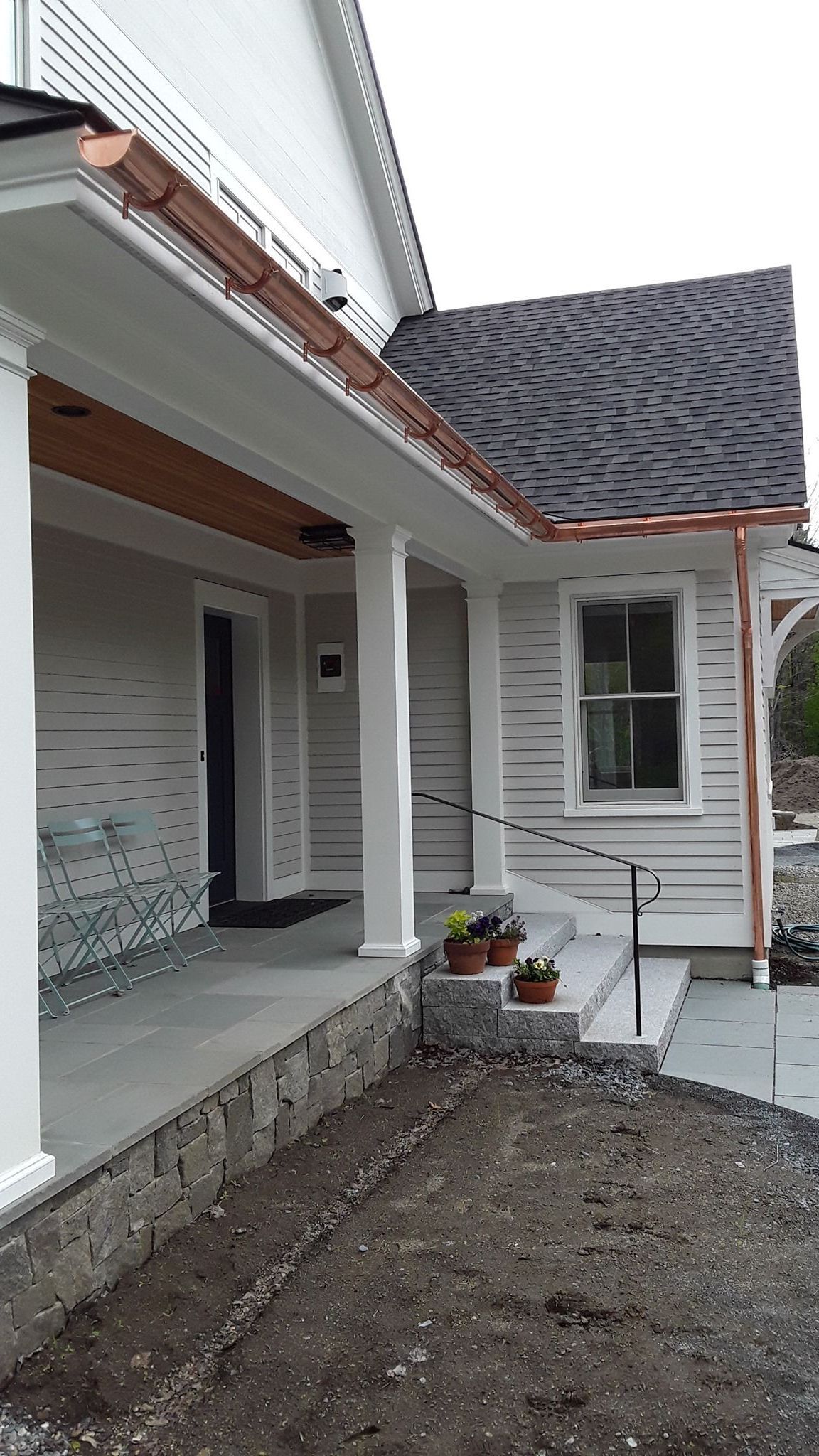 A white house with a porch and a copper gutter.