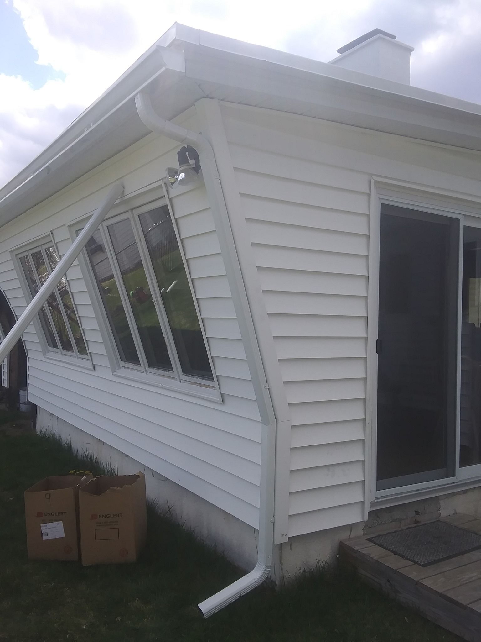 A white house with a sliding glass door and a gutter