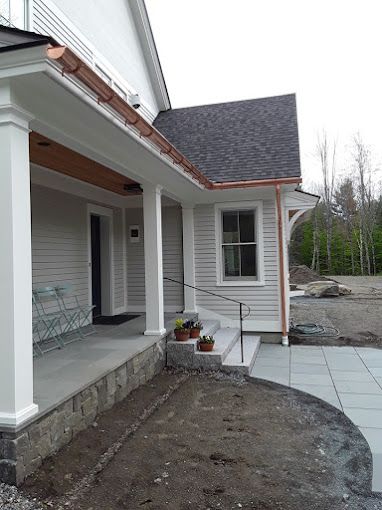 A white house with a copper gutter on the side of it.