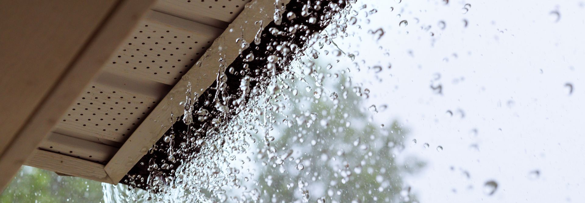 an overflowing rain gutter drenches everything below, inidcating it's time for maintenance or replacement