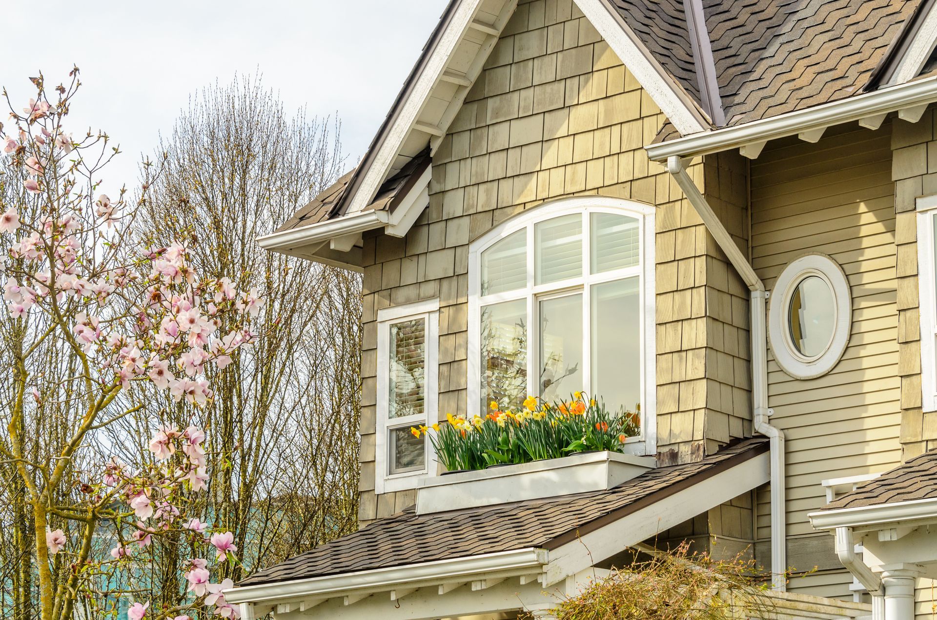 House with rain gutters installed in cloudy spring weather, with a flower box with planted tulips.