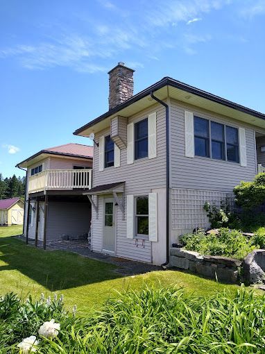 A large house with a chimney on top of it is sitting on top of a lush green hillside.
