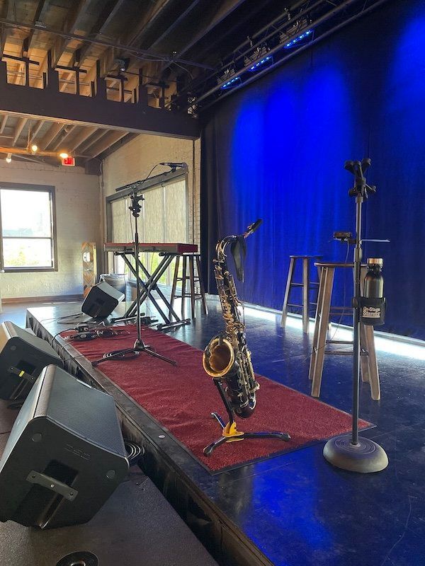 A saxophone is sitting on a stage in front of a blue curtain.