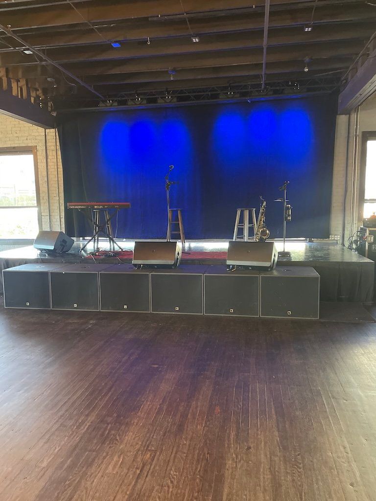 A large empty room with a stage and blue lights.