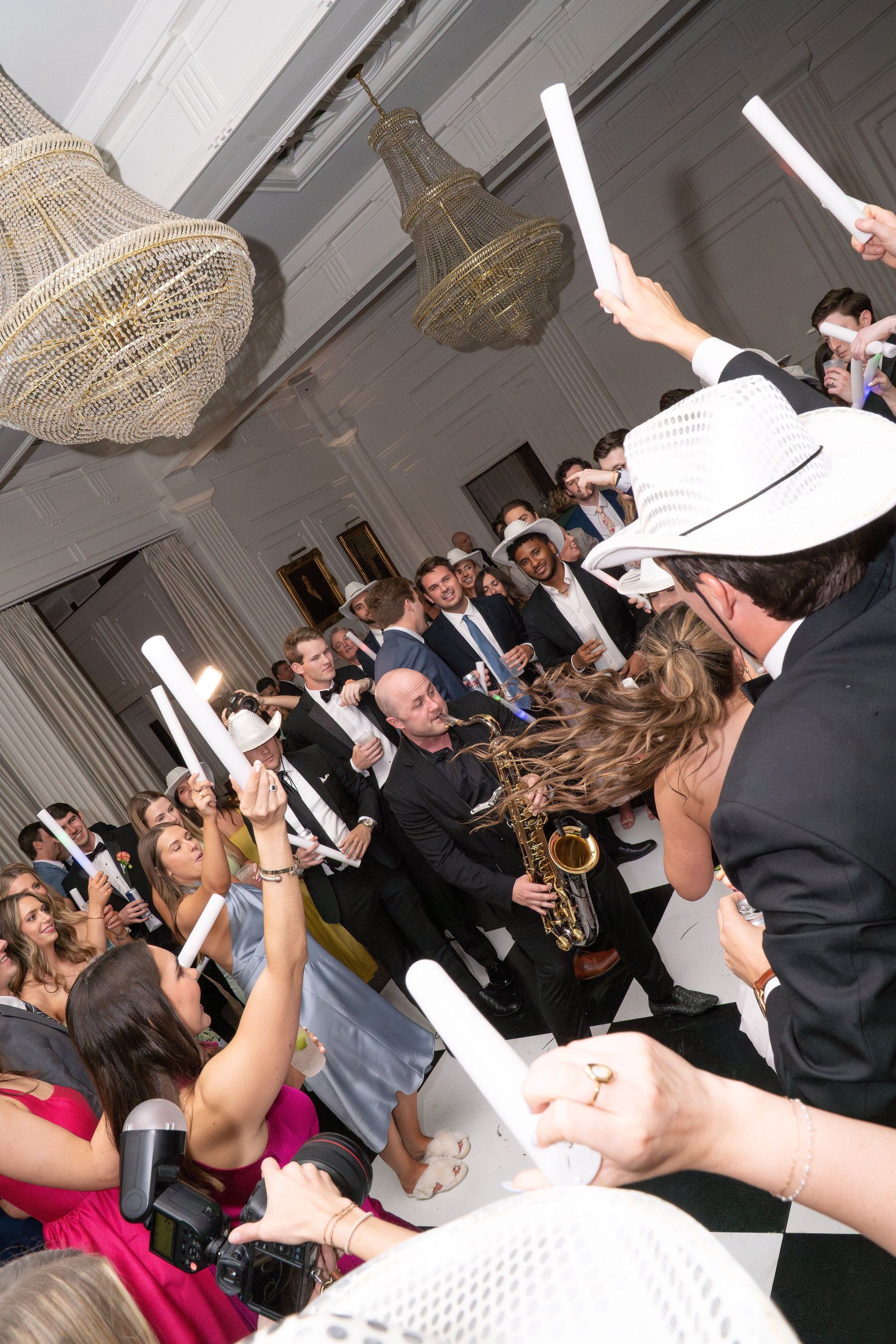 A man is playing a saxophone in front of a crowd of people at a wedding reception.