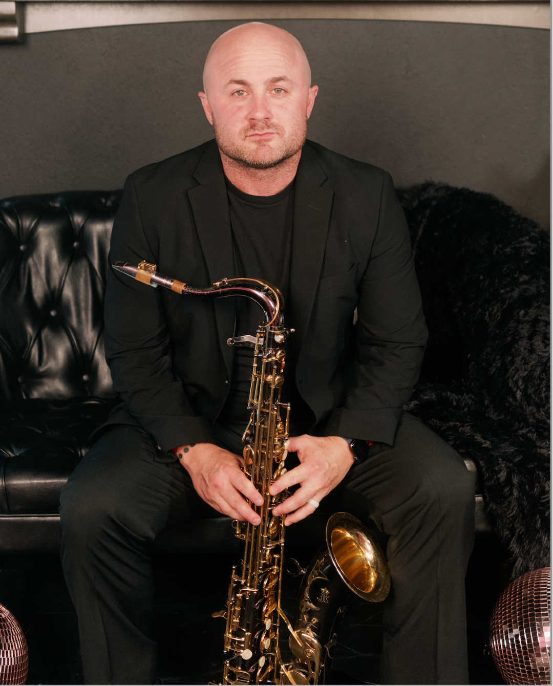 A man is sitting on a couch holding a saxophone