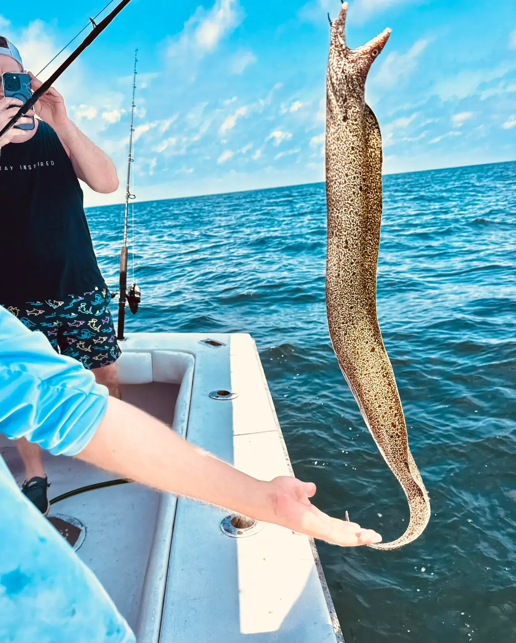 A man is taking a picture of a fish on a boat