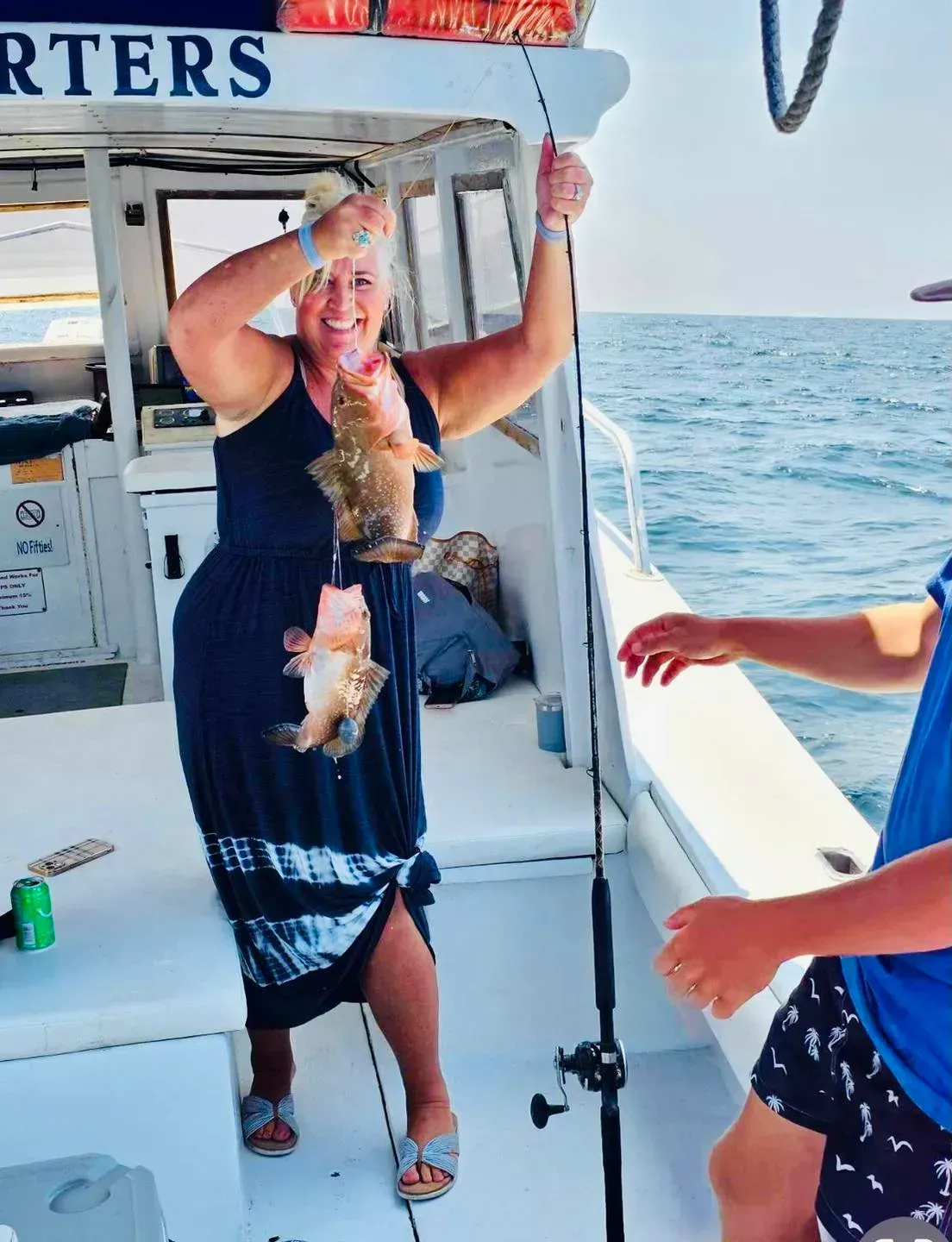 A woman is holding a fish on a boat that says charters