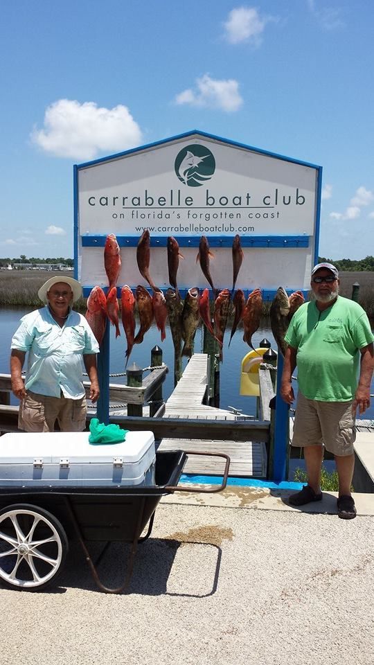 Two men are standing in front of a sign that says carroll 's boat club